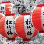 A vibrant display of red and white paper lanterns suspended from a tree, creating a festive atmosphere.